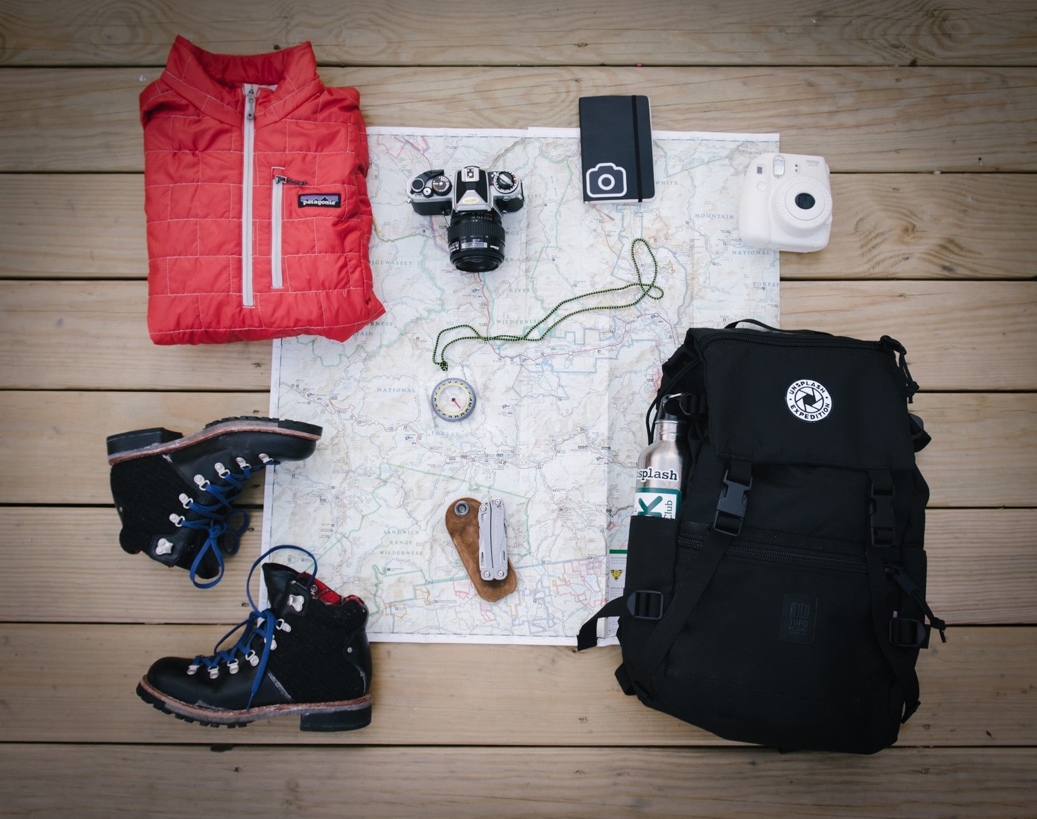 a world map with shoes, jacket, compass and a bag on it